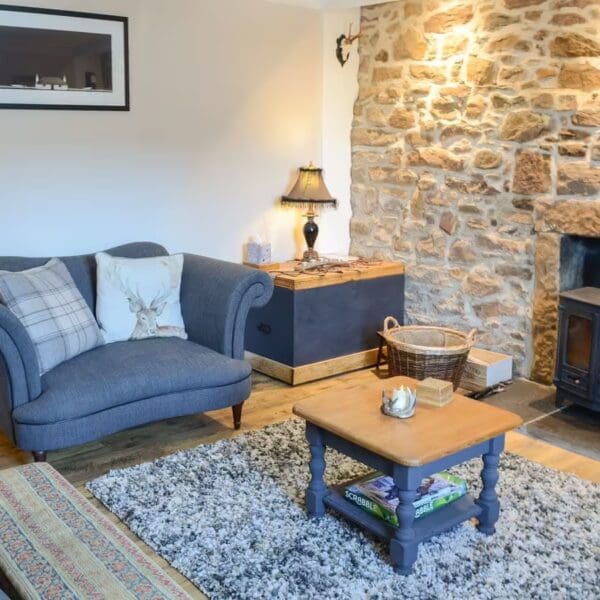 Living room, Wallace House holiday home, Dornoch with navy winged armchair and woodburning stove