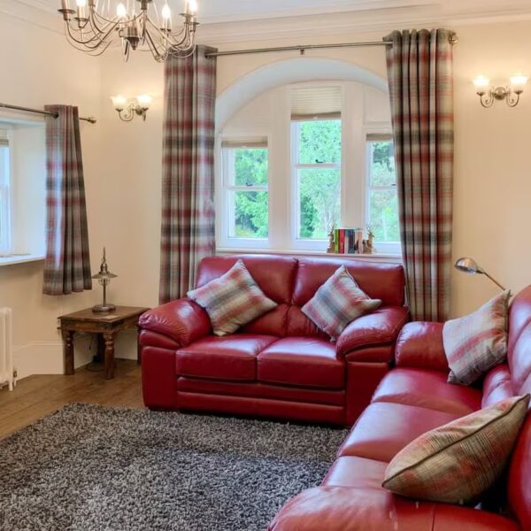 Lounge with red couches and tartan curtains, Sluice Keeper's Cottage, Dornoch