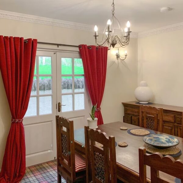 Dining room with red curtains and dark wood table, Sluice Keeper's Cottage, Dornoch