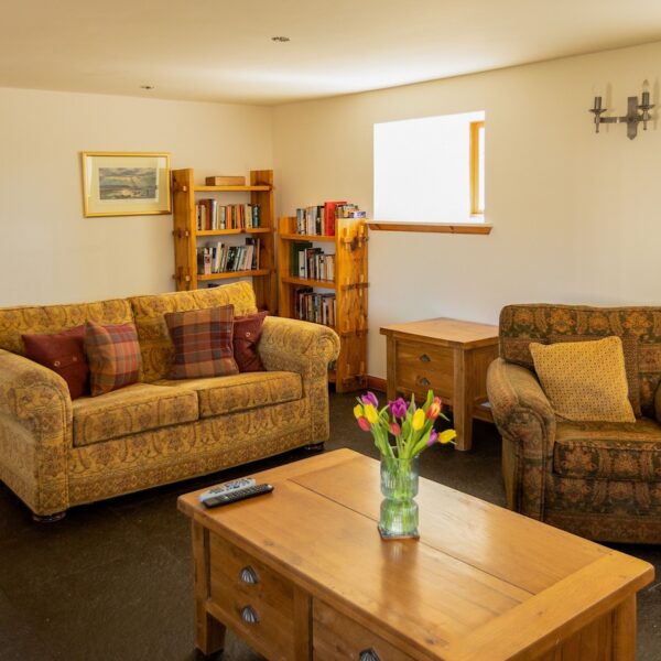 Living room area with yellow suite and pine furniture in Balvraid Steading, near Dornoch