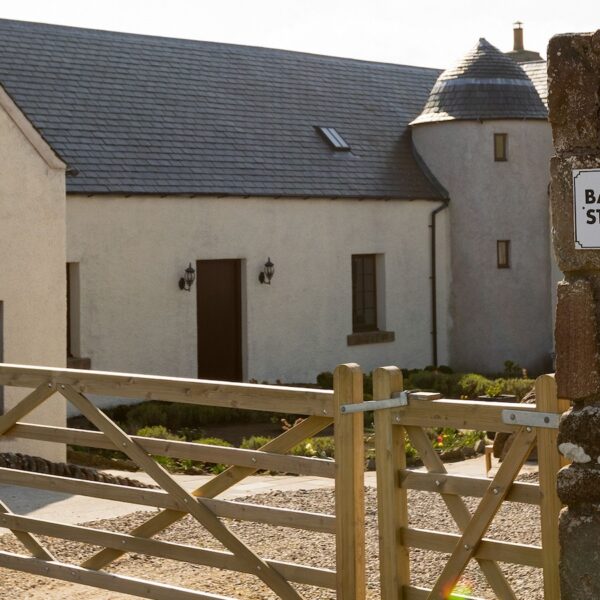 Rear exterior of Balvraid Steading, near Dornoch with wooden entrance gate and house name sign