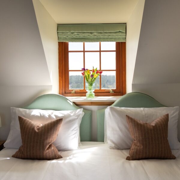 Double bedroom with dormer window and tulips in vase in Balvraid Steading, near Dornoch