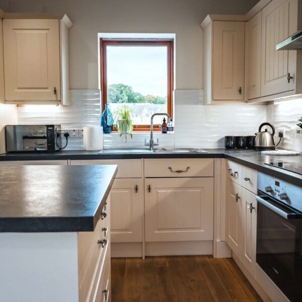 Kitchen with cream cabinets and black counter tops in Grieve's Cottage, Skelbo Dornoch