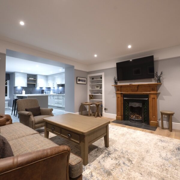 Living room of 2 Quail, Dornoch with grey decor, wooden fireplace surround and large screen tv