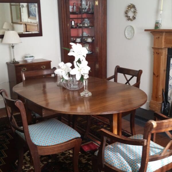 Dining room of Gleann Gollaidh with fireplace and dark wood table with flower arrangement