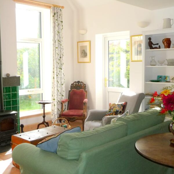 Living room of The Curling Pond, Dornoch with wood burning stove and green couch