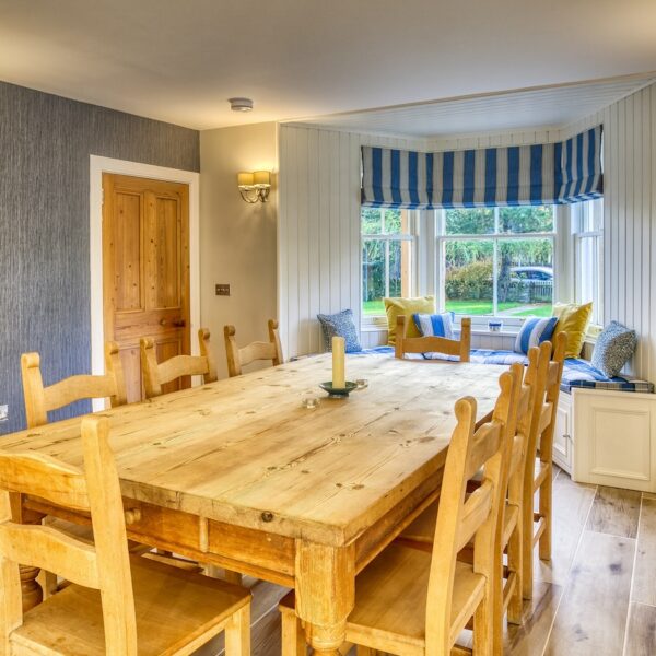 Dining room area in The Meadows, Dornoch with grey wallpaper and large pine table and chairs