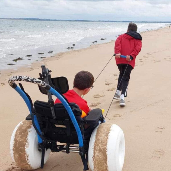 Boy being towed along Dornoch Beach in wheelchair