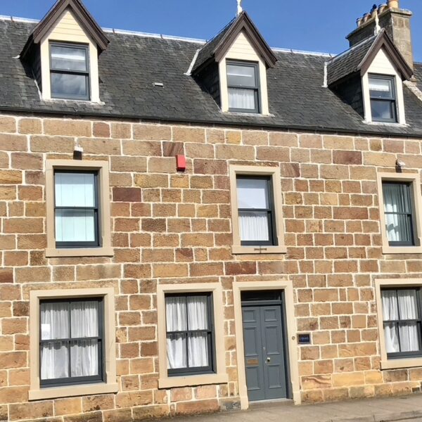 South facing frontage of 2 Quail, Castle Street, Dornoch with grey door and sandstone stonework