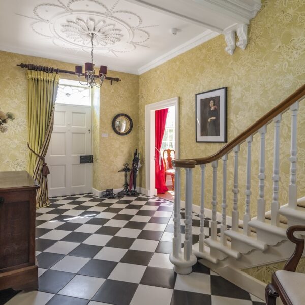 Entrance Hall of Embo House, Dornoch with black and white tiled floor and yellow wallpaper