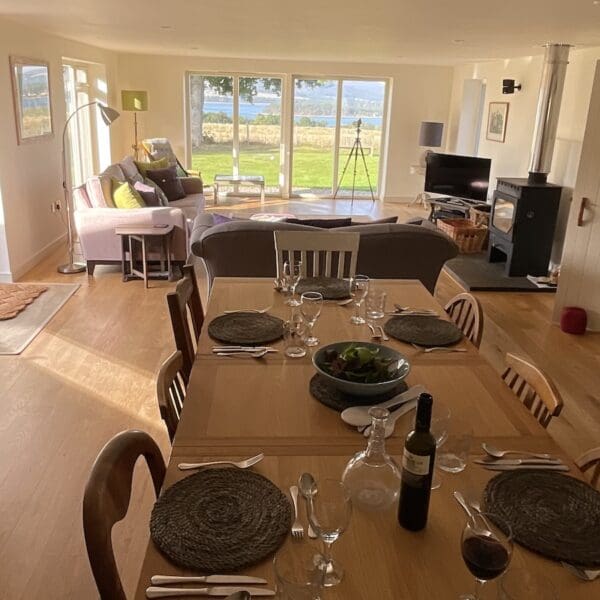 Dining table set with placemats and red wine in living area of Farthingworth holiday rental home, Skelbo, Dornoch