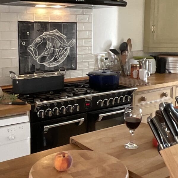 Kitchen with wooden cabinets, red wine glass on counter top and knife block in foreground of Farthingworth holiday rental home, Skelbo, Dornoch