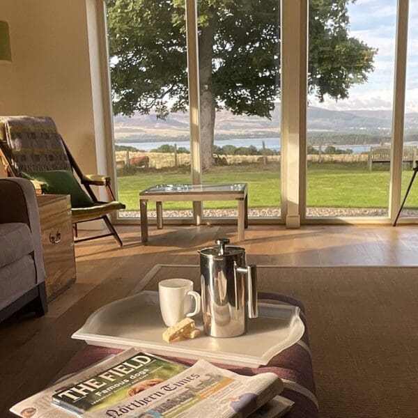 Living room area with large picture window and coffee tray on footstool in Farthingworth holiday rental home, Skelbo, Dornoch