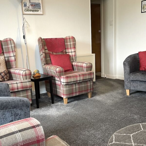 Living room of Oystercatcher, Gate Street, Embo with grey carpet and armchairs, plus red tartan armchairs