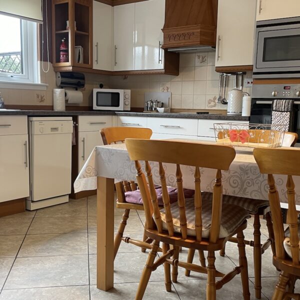 Kitchen of Oystercatcher, Gate Street, Embo with pine table and chairs and white laminate kitchen cabinets