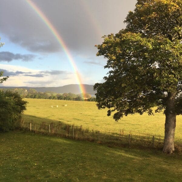 Double rainbow over grass fields with hills in background at Farthingworth holiday rental home, Skelbo, Dornoch