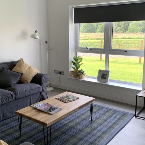 Living room of 2 Sorley Avenue Dornoch with white walls, blue tartan rug and grey couch