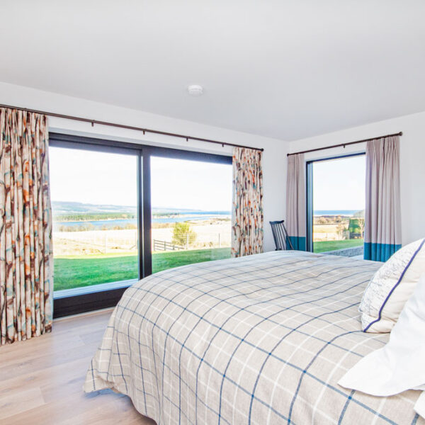 Double bedroom with views north over Loch Fleet from double aspect floor to ceiling windows, Oran Mor, self catering house in Skelbo, Dornoch