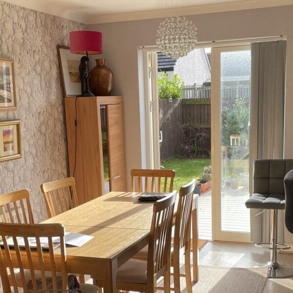 Open plan kitchen diner in 7 Grant Crescent, Dornoch, with pine dining table and patio doors to enclosed garden