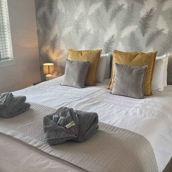 Bedroom in 7 Grant Crescent Dornoch, with grey patterned wallpaper and yellow accent cushions