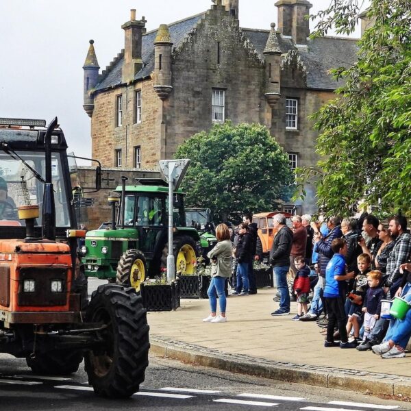 Tractors leaving Dornoch Square with crowd of people watching