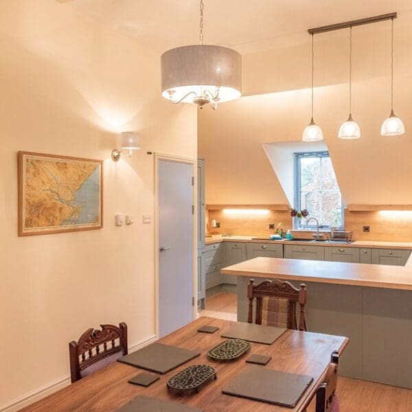 Kitchen and dining area with light blue kitchen cabinets, hanging lights and darkwood dining table in Dornoch Mews, Dornoch, Highlands