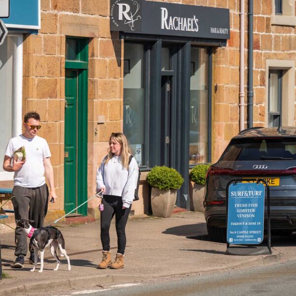 Couple with dog outside Surf & Turf, Castle Street Dornoch