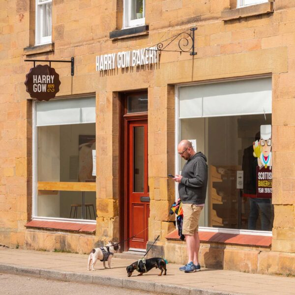 Man with dogs outside Harry Gow bakery Dornoch