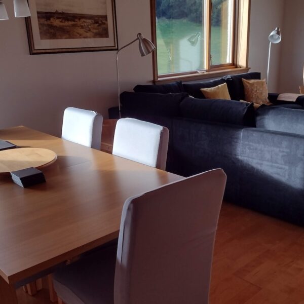 Dining and living area in Wester Whinhill, Dornoch with pine dining table and grey couch