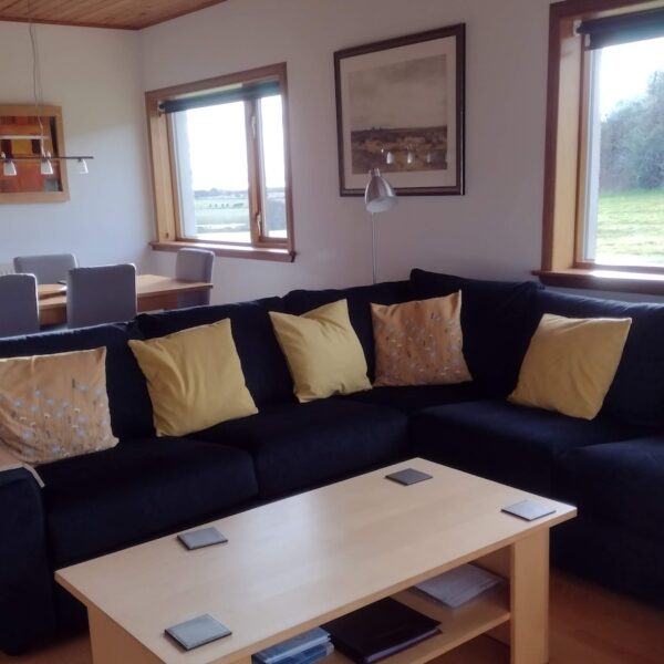 Dining and living area in Wester Whinhill, Dornoch with large dark grey L-shaped couch and pine coffee table