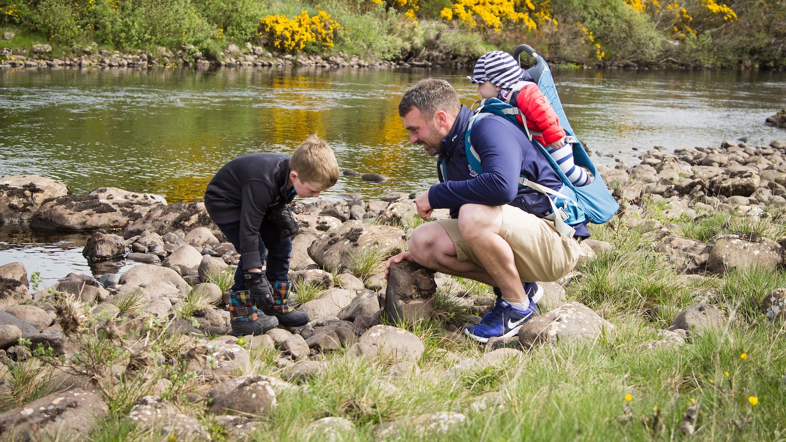 father and two children next to riverbank