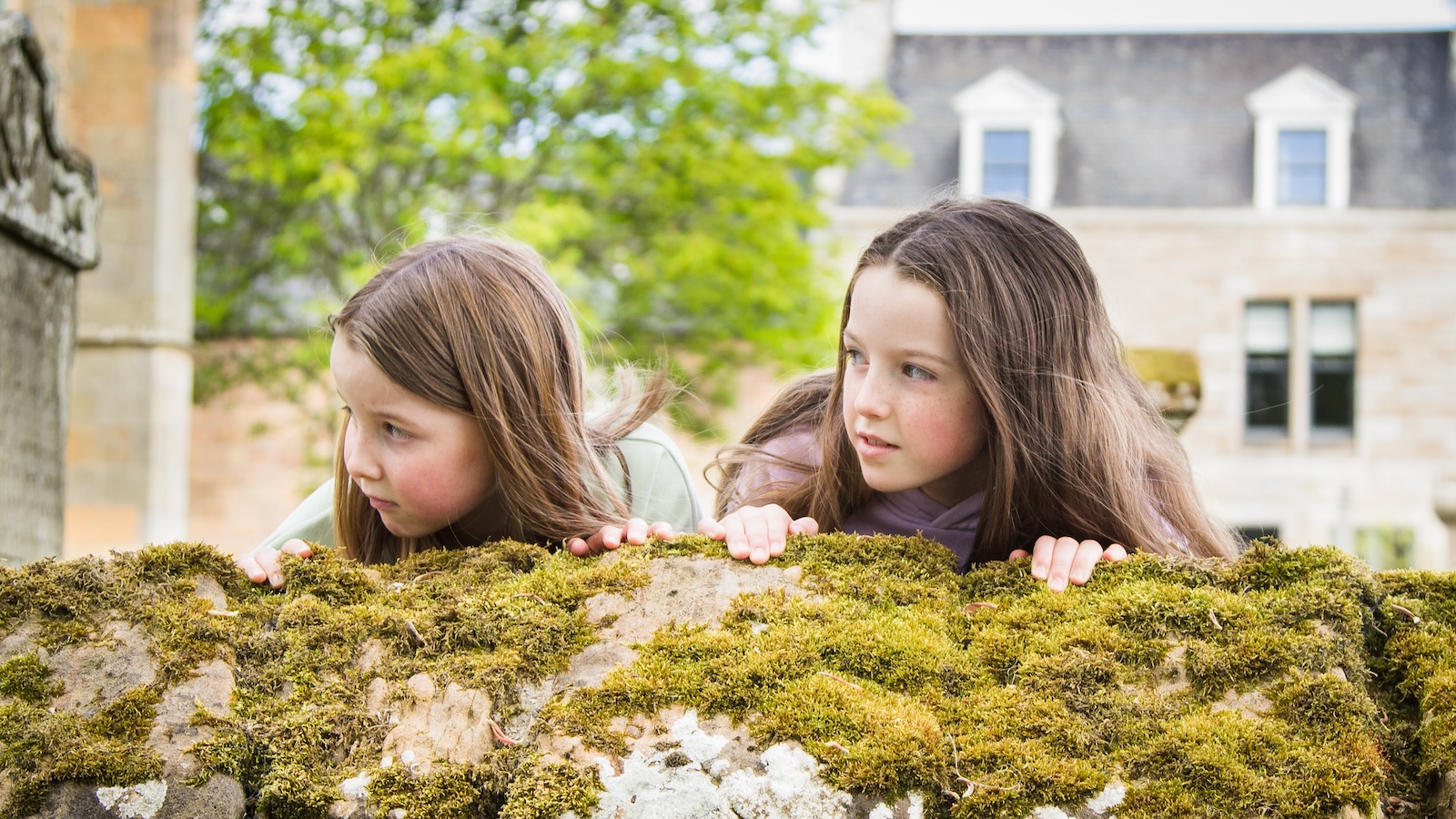 Two girls looking over top of graveyard wall, Dornoch Cathedral