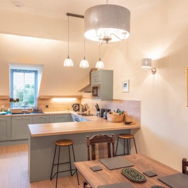 Open plan kitchen and dining area with light blue kitchen cabinets and oak countertops in Dornoch Mews, Dornoch, Highlands