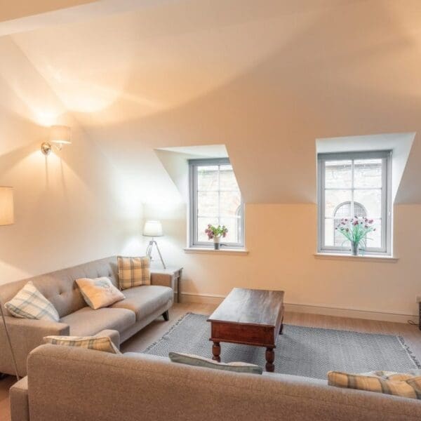 Living room with grey sofas, darkwood coffee table, wide screen tv and standard lamp in Dornoch Mews, Dornoch, Highlands