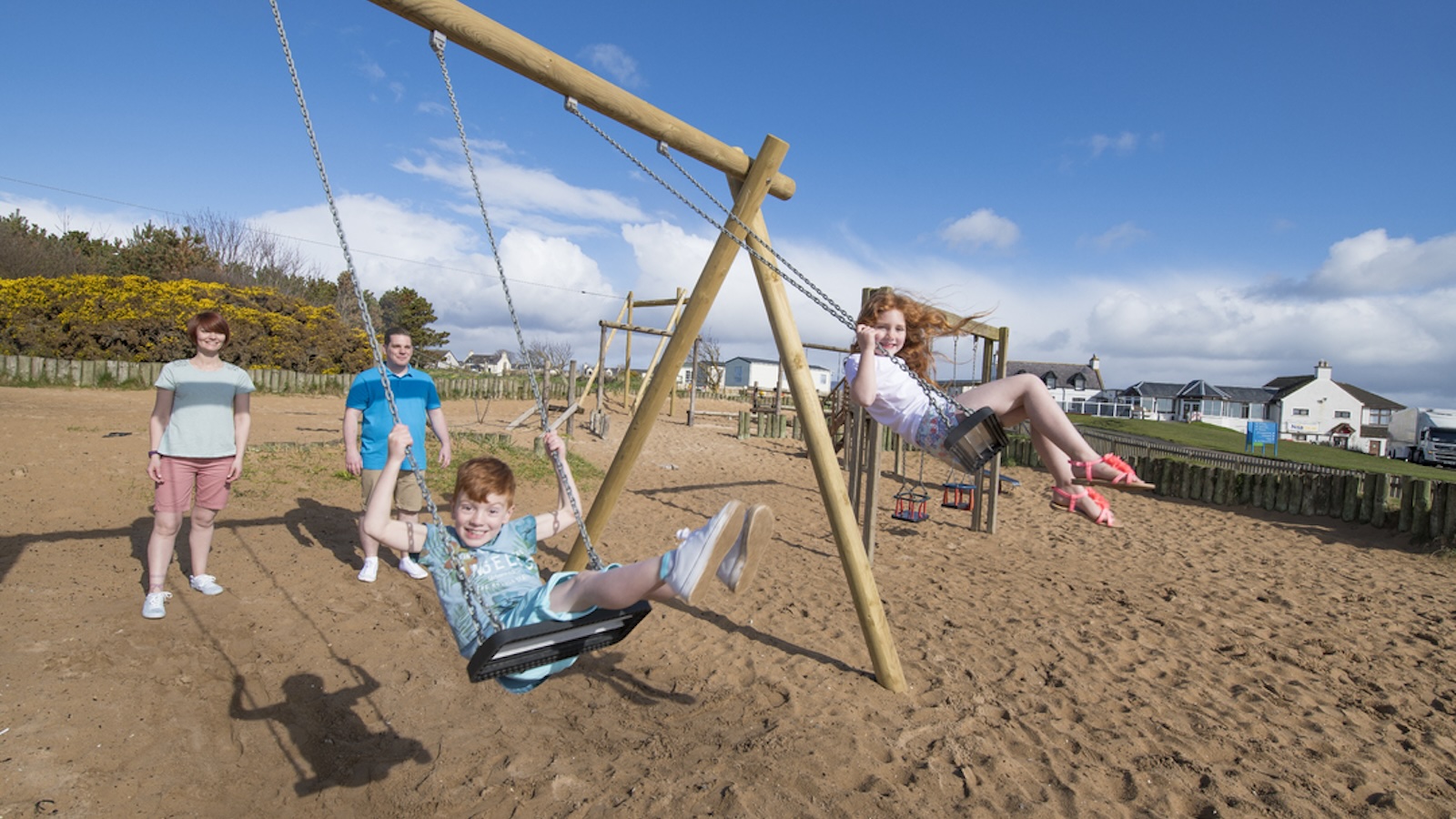 Family on swings at Grannies Heilan Haim caravan park, Embo, Dornoch