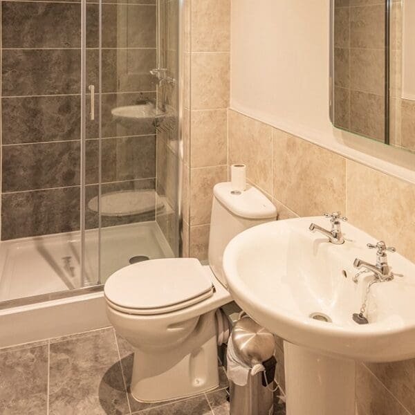 Shower room and toilet with grey and cream tiling in Dornoch Mews, Dornoch, Highlands