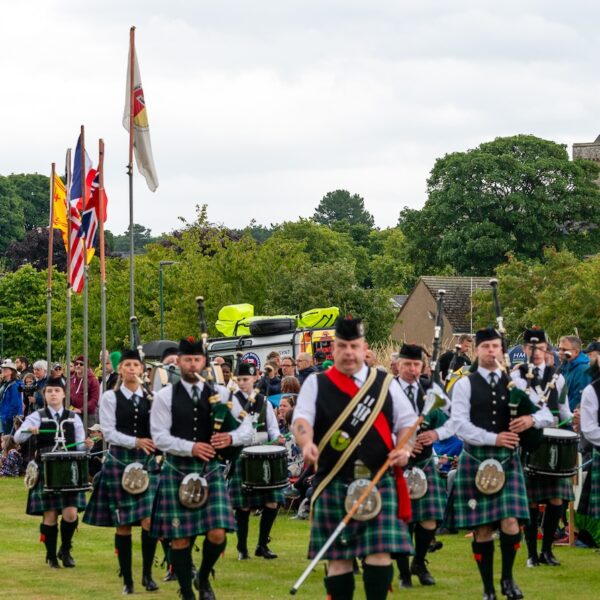 Piped band at Dornoch Highland Games with Cathedral in Background