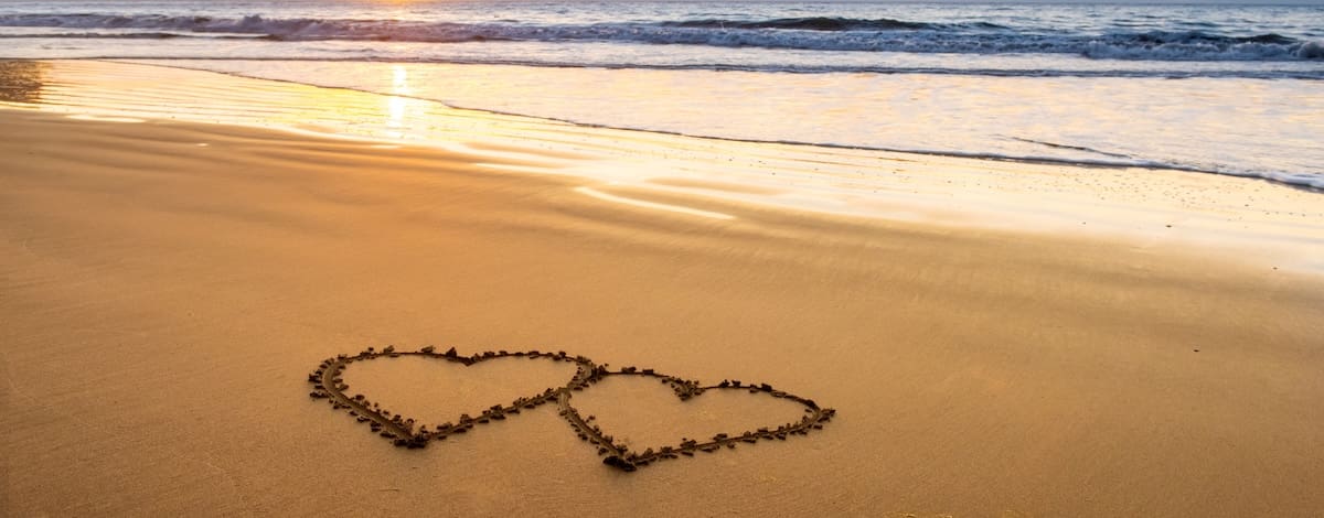 Hearts drawn in sand on beach 1200x470