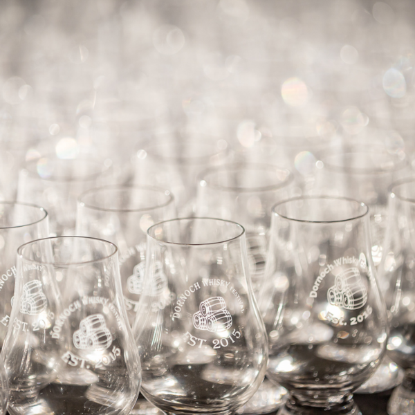 Multiple Glencairn whisky glasses showing Dornoch Whisky Festival on a table