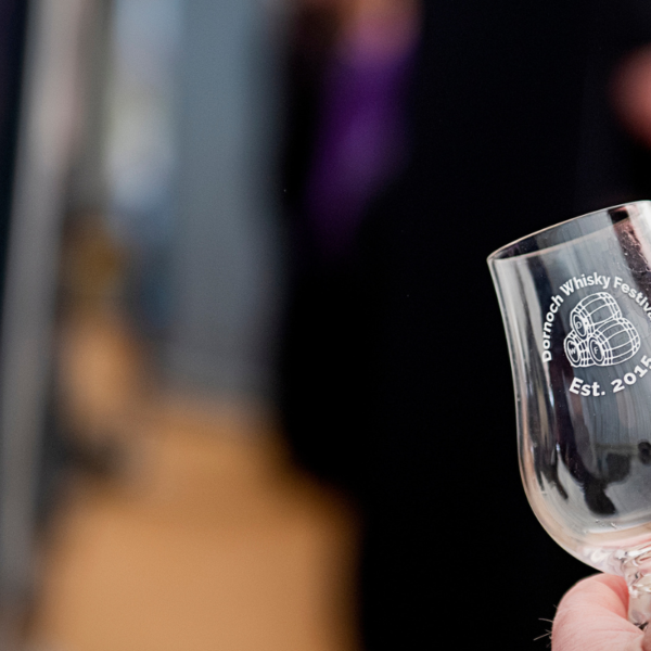 Single Dornoch Whisky Festival branded Glencairn glass being held