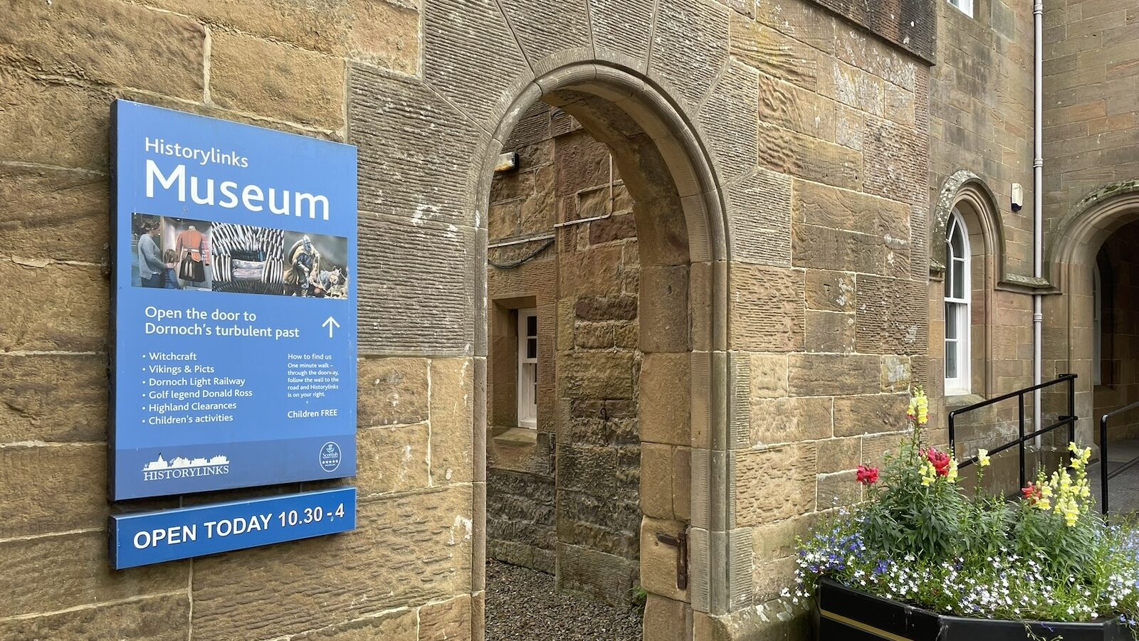 Sign for Historylinks Museum next to archway in wall, Castle Street Dornoch